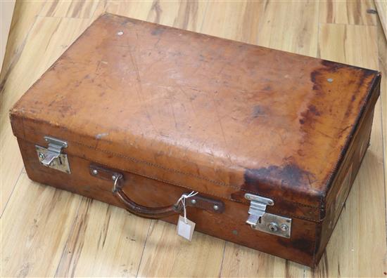 A tan leather suitcase with Deco label